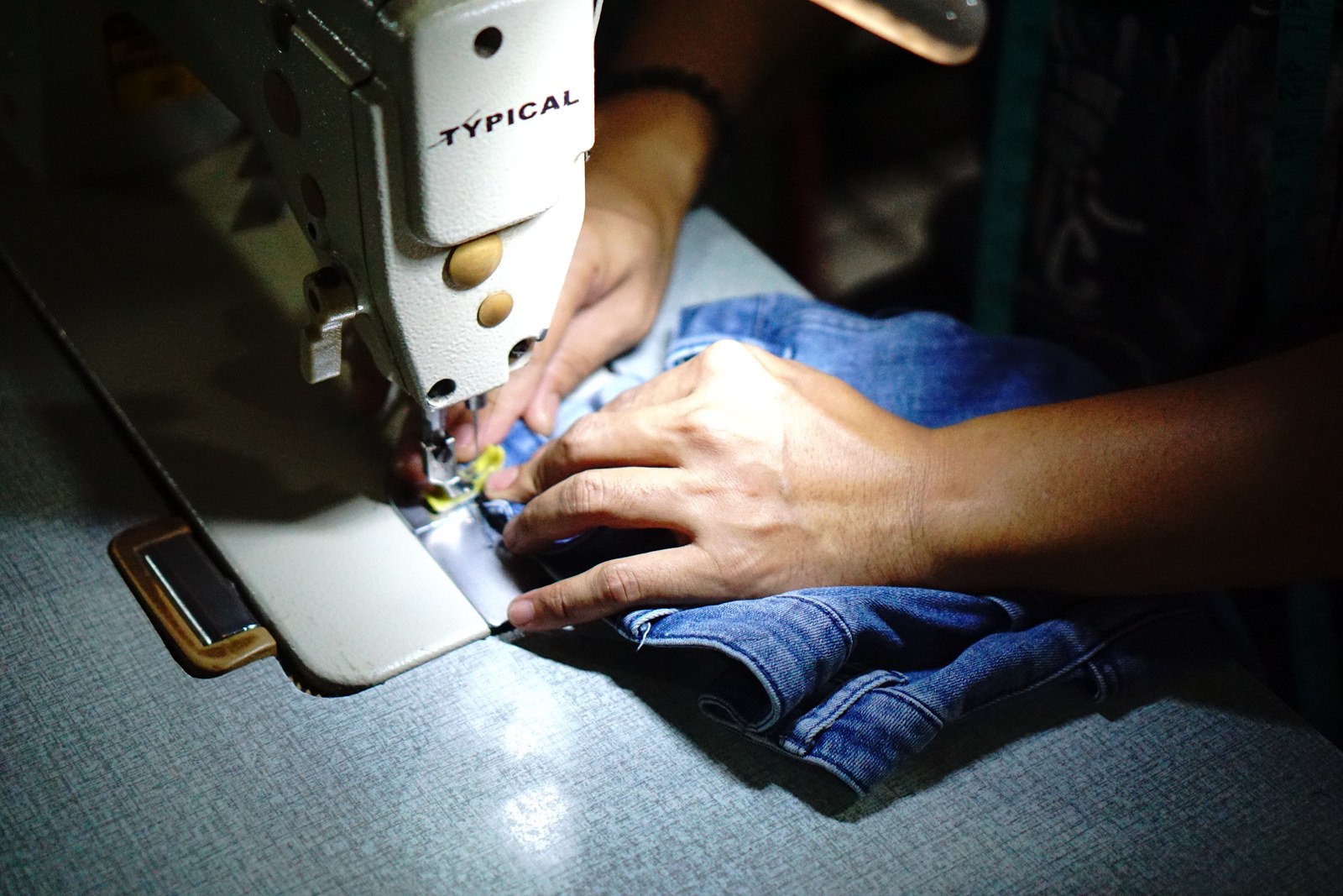 Máquina de coser moderna cosiendo bajos de pantalones vaqueros en el taller de María Almería